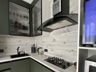 Маленькая угловая зеленая кухня с отдельно висящей вытяжкой